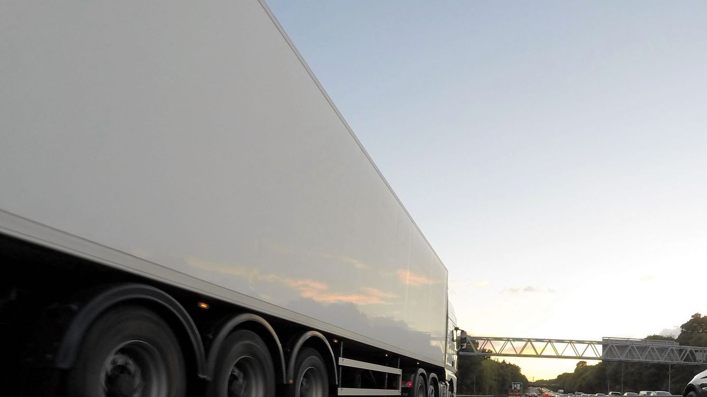 A plain white lorry trailer on a UK motorway at dusk